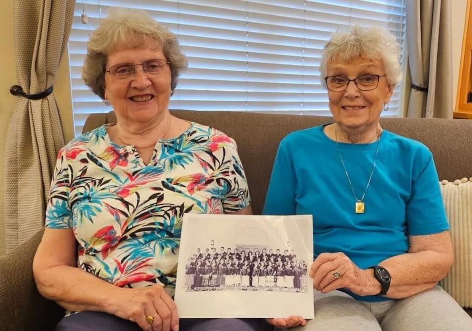 Sylvia Crane and Joan Harris holding their school yearbook photo.