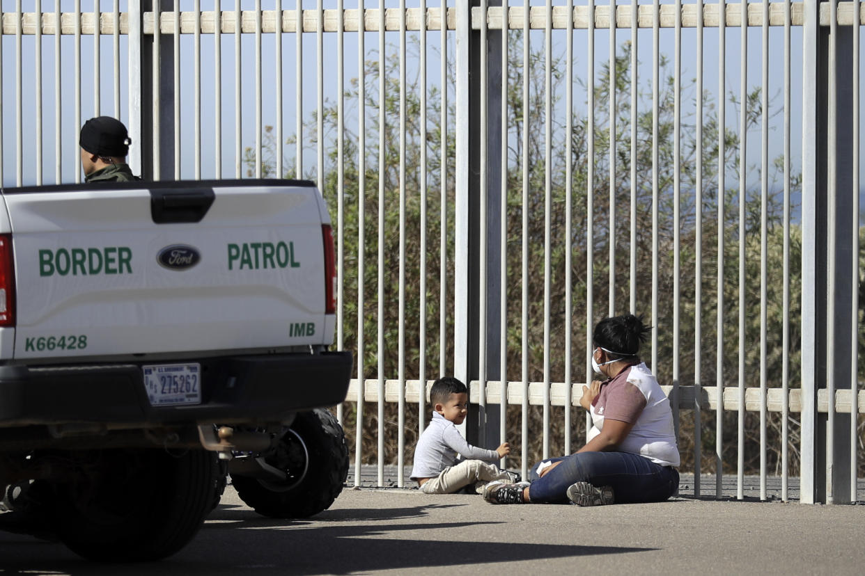 A woman and a child are detained by U.S. Border Patrol agents between two border structures on the U.S. side of the southern border Tijuana, Mexico, on Nov. 15, 2018. (Photo: Gregory Bull/AP)