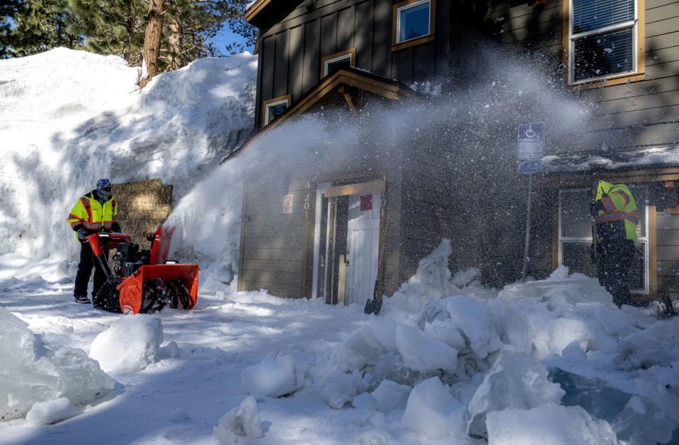 Workers in Mammoth Lakes clear snow from an apartment building.