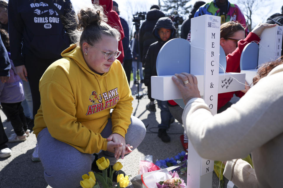 Delanie Palmer, friend of Jenna Newcomb, crouches near a cross for Newcomb during a vigil Thursday, March 28, 2024, for the victims of Wednesday's stabbings in Rockford, Ill (Eileen T. Meslar/Chicago Tribune via AP)