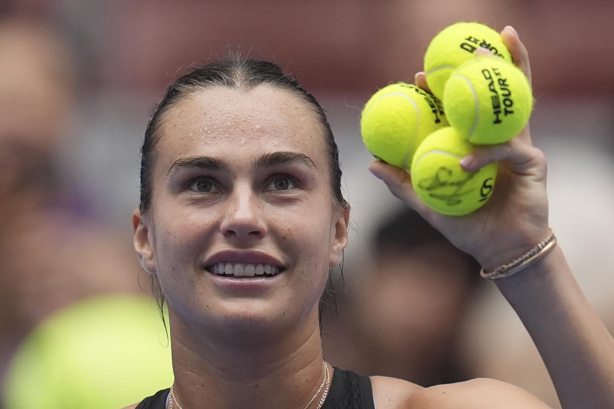 Aryna Sabalenka of Belarus holds up autographed tennis balls to share with fans after her match against Mananchaya Sawangkaew of Thailand during the China Open tennis tournament held at the National Tennis Center in Beijing, Saturday, Sept. 28, 2024. (AP Photo/Ng Han Guan)