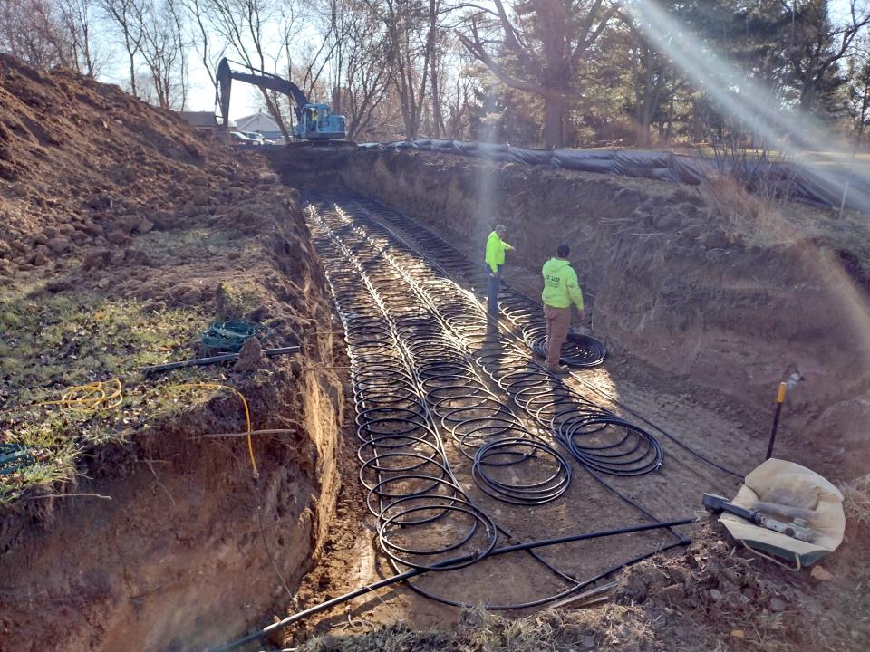 Workers from G. O. Loop of Fox Lake install a horizontal loop field about 8 feet below the surface for a geothermal heating and cooling system for a new Cudahy ranch-style home.