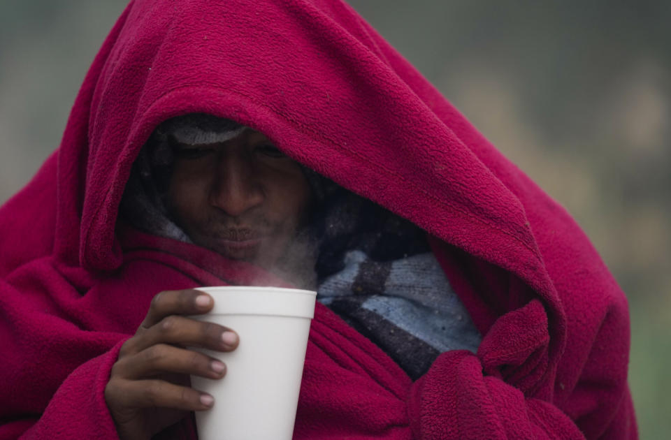 A migrant from Venezuela drinks a hot coffee amid cold weather at a makeshift camp along the Rio Grande riverbank on the U.S.-Mexico Border in Matamoros, Mexico, Friday, Dec. 23, 2022. Migrants are waiting on a pending U.S. Supreme Court decision on asylum restrictions. (AP Photo/Fernando Llano)