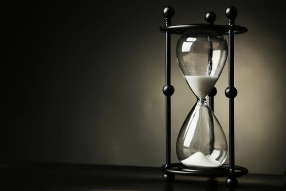 Black-framed hourglass with roughly half of the sand at the bottom