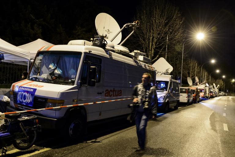 A press photographer walks along news television vehicles parked in front of the hotel Beau-Rivage Palace during Iran nuclear talks in Lausanne late on March 31, 2015