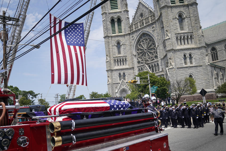 The casket of Newark firefighter Augusto "Augie" Acabou departs aboard a firetruck hearse after being carried from the Cathedral Basilica of the Sacred Heart during his funeral days after he died battling a fire aboard the Italian-flagged Grande Costa d'Avorio cargo ship at the Port of Newark, Thursday, July 13, 2023, in Newark, N.J. The fire also claimed the life of Wayne "Bear" Brooks Jr. (AP Photo/John Minchillo)