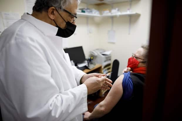 Pharmacist Abraam Rafael administers a COVID-19 vaccine to Maureen Doyle at his pharmacy in Toronto. 