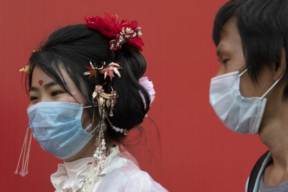 Residentes usan mascarillas para ayudar a contener la propagación del coronavirus mientras caminan en una calle comercial en Wuhan, provincia de Hubei, China, el jueves 9 de abril de 2020. (AP Foto/Ng Han Guan)