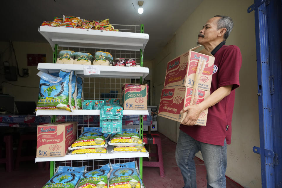 Mukroni, de 52 años, coloca cajas de tallarines en su tienda de Bekasi, a las afueras de Yakarta, Indonesia, el jueves 2 de febrero de 2023. Casi un año después de que Rusia invadiera Ucrania, los altos precios de la comida castigan especialmente a los pobres del mundo. Los clientes, dijo Mukroni, “no vendrán a la tienda” si los precios son demasiado altos. (AP Foto/Achmad Ibrahim)