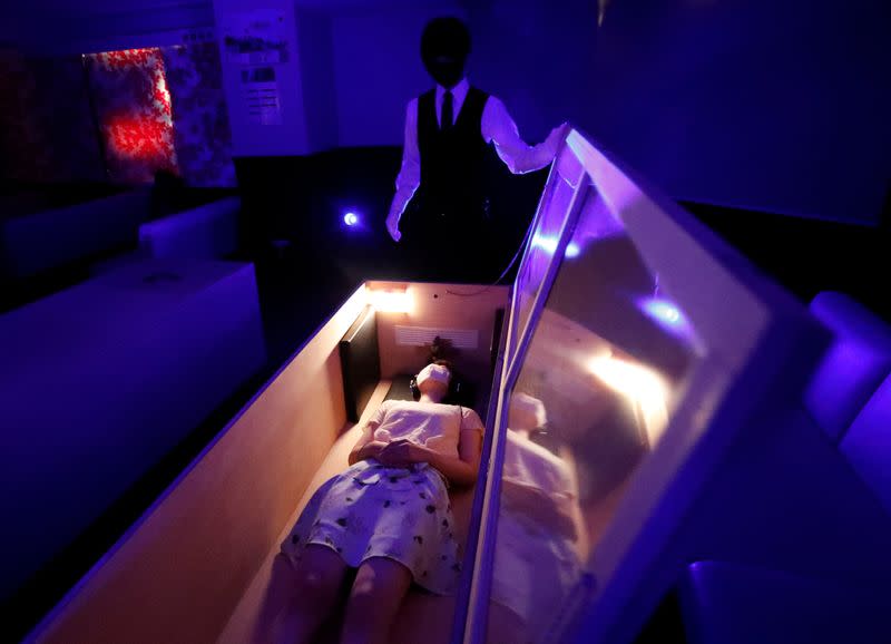 A participant lies inside a mock of coffin with plastic shields to maintain social distancing amid the spread of the coronavirus disease (COVID-19), during a coffin horror show, in Tokyo