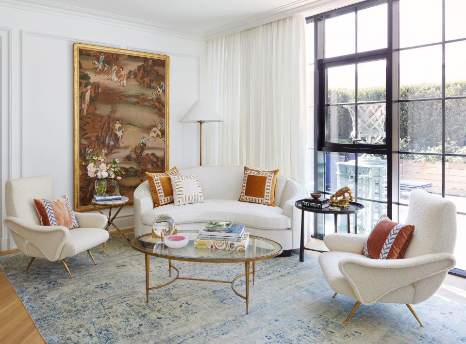 In the formal sitting room, a sofa by Jonas upholstered in Pierre Frey fabric is adorned with pillows trimmed in Michael Aiduss for Houlès collection trimmings. The bronze cocktail table is from Porta Romana, and the 18th-century Chinese hand-painted wallpaper panel is from the Gerald Bland gallery.