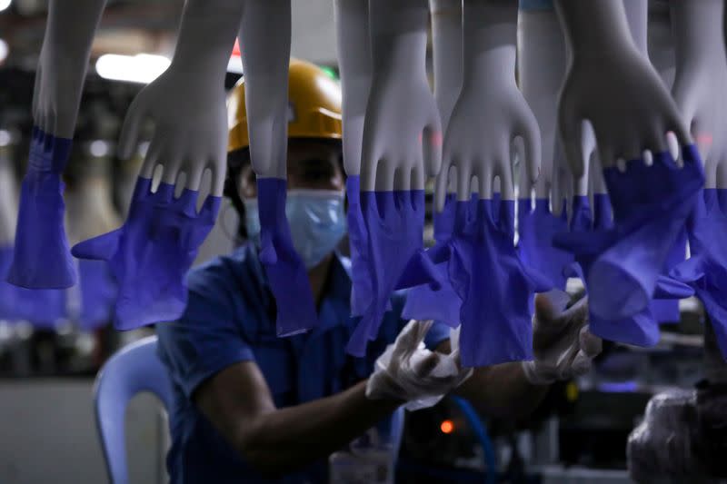 FILE PHOTO: A worker inspects newly made gloves at a Top Glove factory in Shah Alam