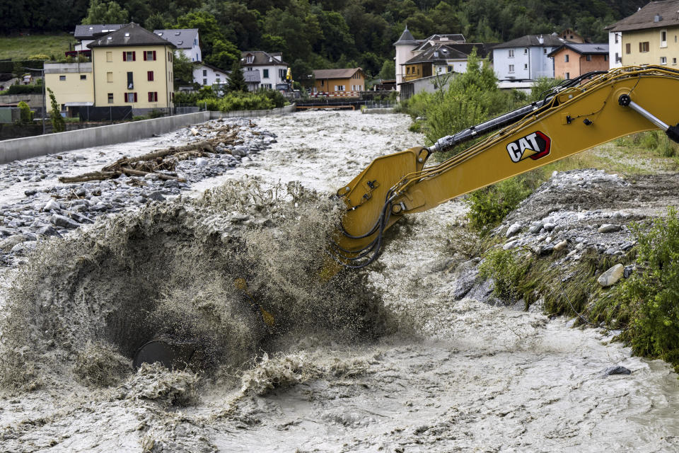 An excavator removes stones from the bed of the Navizence river, which flows into the Rhone, in Chippis, canton Valais, Switzerland, Saturday June 22, 2024. (Jean-Christophe Bott/Keystone via AP)