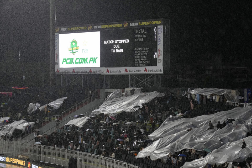 Fans cover themselves in plastic sheets as rain stop the play of first T20 cricket match between Pakistan and New Zealand, in Rawalpindi, Pakistan, Thursday, April 18, 2024. (AP Photo/Anjum Naveed)