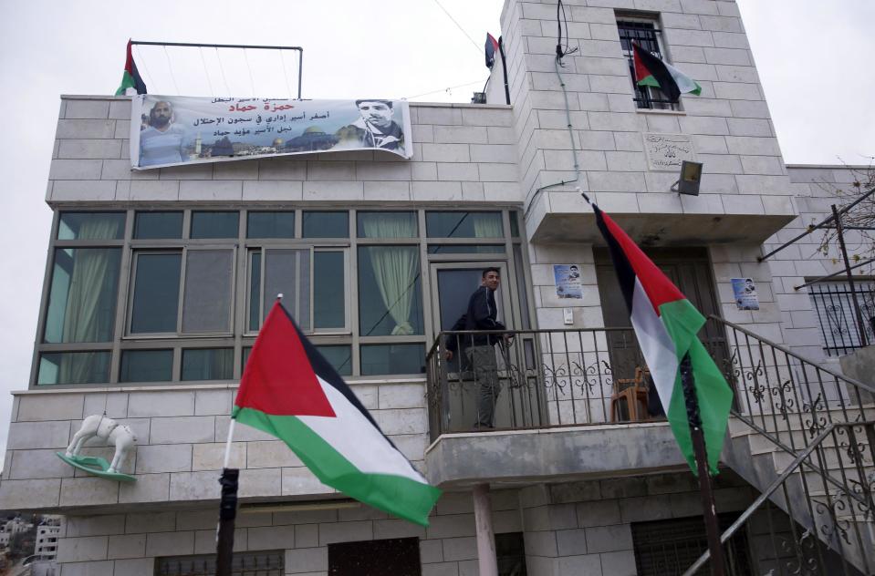 In this Thursday, Jan. 5, 2017 photo, Palestinian Hamza Hamad, walks out of his house, in the village of Silwad, east of the West Bank city of Ramallah. High school student Hamza Hamad spent 10 months in an Israeli jail, but was never charged with a crime. The 16-year-old is one of the youngest among thousands of Palestinians who have been held in administrative detention in half a century of Israeli military occupation. The banner on the house protests his detention. (AP Photo/Majdi Mohammed)