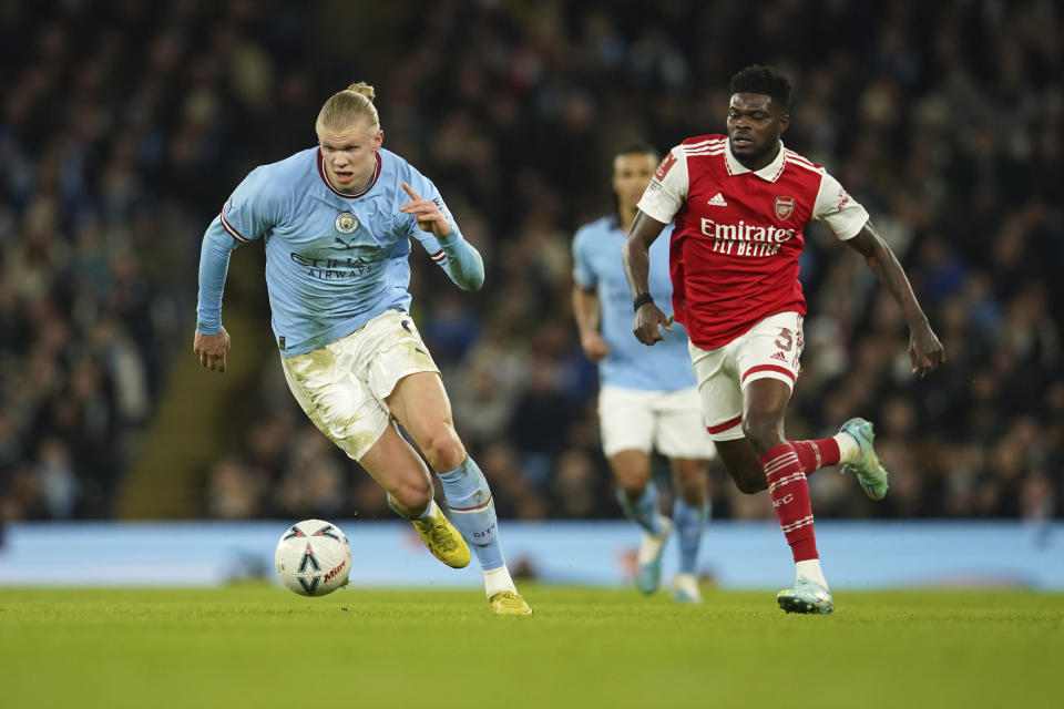 Manchester City's Erling Haaland, left, dribbles past Arsenal's Thomas Partey during the English FA Cup 4th round soccer match between Manchester City and Arsenal at the Etihad Stadium in Manchester, England, Friday, Jan. 27, 2023. (AP Photo/Dave Thompson)