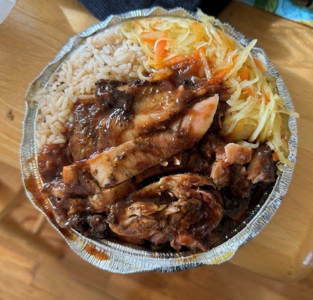 A plate of jerk chicken, sauteed cabbage, and rice and peas from Island Breeze Bar and Grill.