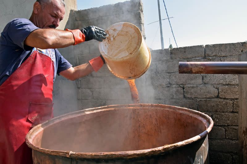 Saad Hussein, an Iraqi Yazidi, pours Arak into a large pot to produce Arak liquor out of dates, on the outskirts of Mosul