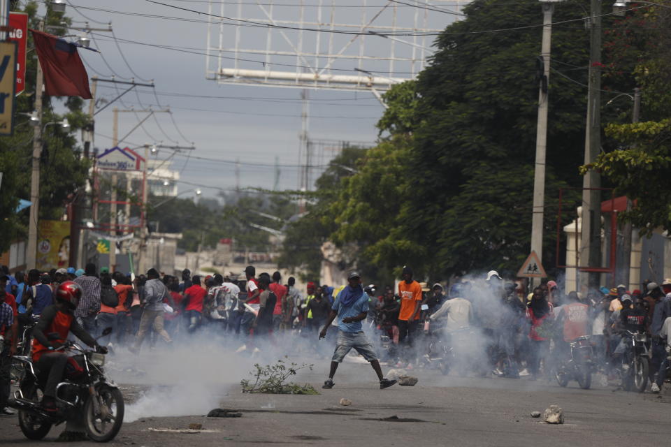 Protesters turn and run as police began to fire tear gas as they gather in Port-au-Prince, Haiti, Monday, Sept. 30, 2019. Opposition leaders are calling for a nationwide push Monday to block streets and paralyze Haiti's economy as they press for Moise to give up power, and tens of thousands of their young supporters were expected to heed the call. (AP Photo/Rebecca Blackwell)