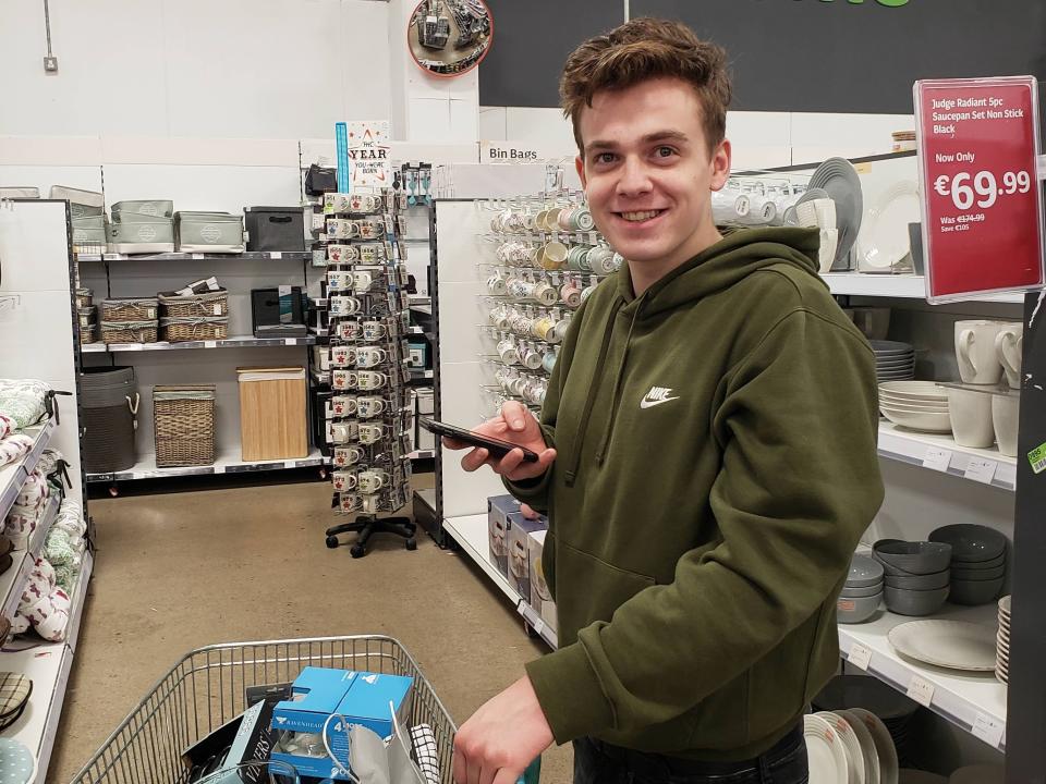 A boy in a green hoodie shopping for home goods at a supermarket in Dublin.