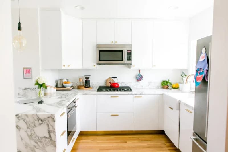 a white kitchen with gray marble countertops