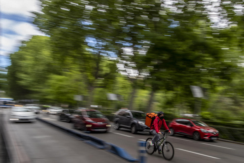 A delivery worker rides his bike in Madrid, Spain, Tuesday, May 11, 2021. Spain has approved a pioneering law that gives delivery platforms a mid-August deadline to hire the workers currently freelancing for them and that requires transparency of artificial intelligence to manage workforces. (AP Photo/Manu Fernandez)