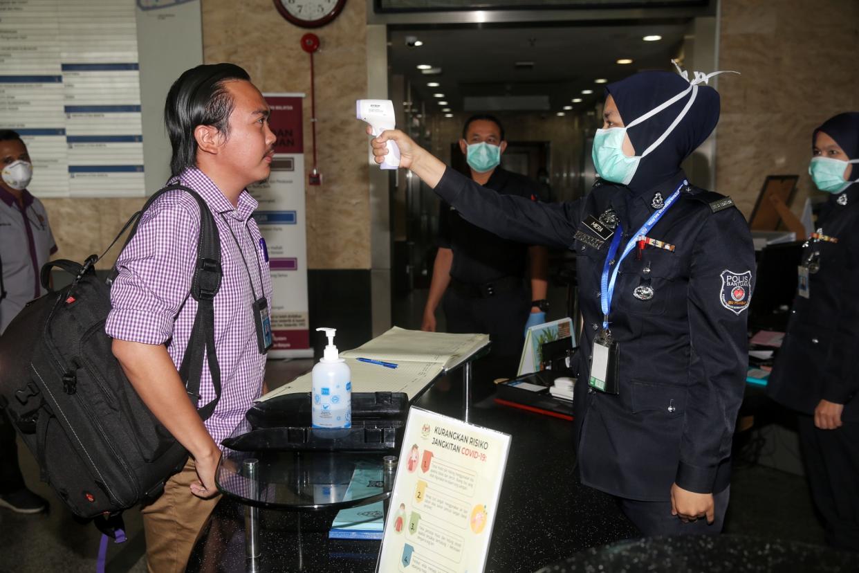 A police personnel records a reporter’s temperature ahead of a Health Ministry press conference in Putrajaya March 19, 2020. — Picture by Choo Choy May