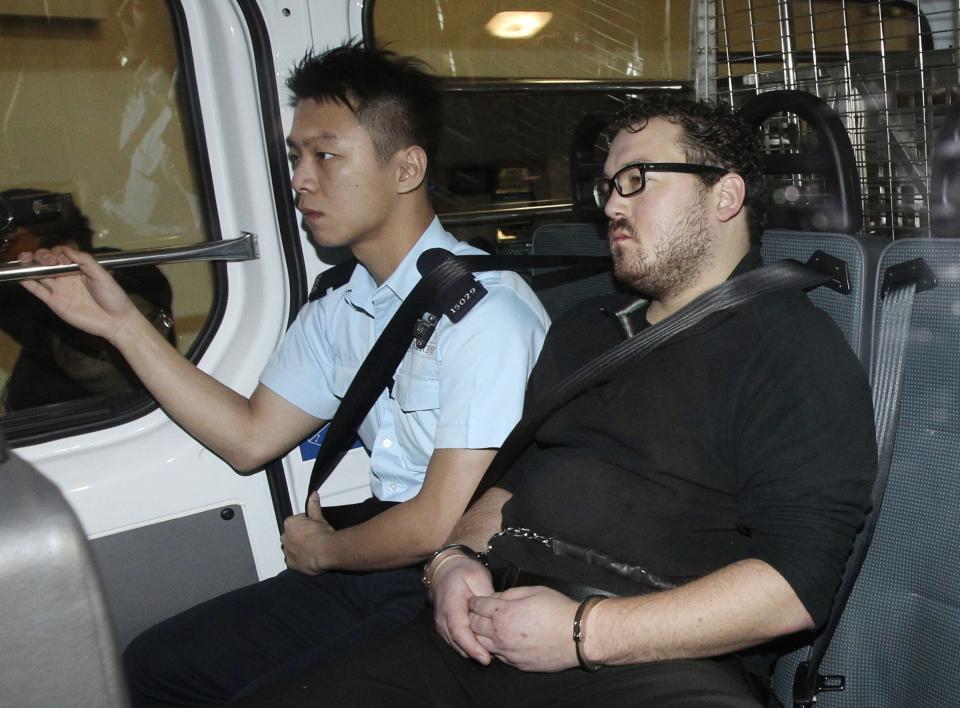 Rurik Jutting (R), a 29-year-old British banker who has been charged with two counts of murder, sits in a police van as it arrives at a court in Hong Kong November 3, 2014. Hong Kong police have charged Jutting with two counts of murder after authorities found the bodies of two women in his apartment, including one that had been hidden in a suitcase on a balcony. REUTERS/Apple Daily (CHINA - Tags: CRIME LAW) ATTENTION EDITORS - THIS IMAGE WAS PROVIDED BY A THIRD PARTY. THIS PICTURE WAS PROCESSED BY REUTERS TO ENHANCE QUALITY. AN UNPROCESSED VERSION WILL BE PROVIDED SEPARATELY. NO SALES. NO ARCHIVES. FOR EDITORIAL USE ONLY. NOT FOR SALE FOR MARKETING OR ADVERTISING CAMPAIGNS. HONG KONG OUT. NO COMMERCIAL OR EDITORIAL SALES IN HONG KONG. TAIWAN OUT. NO COMMERCIAL OR EDITORIAL SALES IN TAIWAN