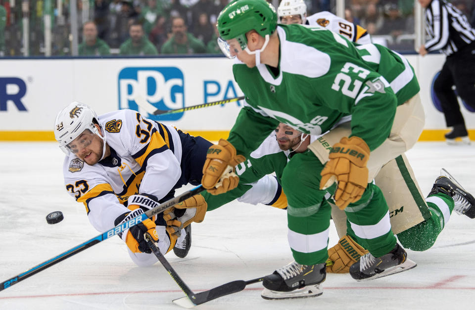 Nashville Predators right wing Viktor Arvidsson (33) dives to the ice as he competes for the puck with Dallas Stars defenseman Esa Lindell (23) and left wing Blake Comeau in the first period of the NHL Winter Classic hockey game at the Cotton Bowl, Wednesday, Jan. 1, 2020, in Dallas. (AP Photo/Jeffrey McWhorter)