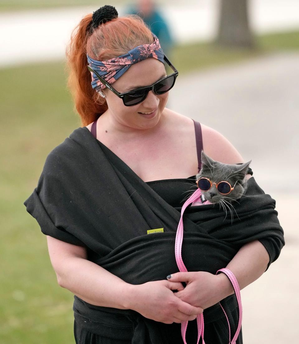 Ainslie Evans, of Milwaukee, takes advantage of the mild spring-like temperatures by taking a walk with her 9-month old cat, Lucia, who is sporting a pair of cat sun glasses at Veteran Park in Milwaukee on Monday, April 10, 2023.