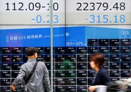 People walk past an electronic board showing Japan's Nikkei average (top R) and Japanese yen's exchange rate against the U.S. dollar outside a brokerage in Tokyo, Japan, October 15, 2018.   REUTERS/Toru Hanai