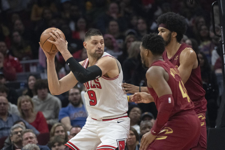 Chicago Bulls' Nikola Vucevic (9) keeps the ball from Cleveland Cavaliers' Donovan Mitchell, right front, and Jarrett Allen during the first half of an NBA basketball game in Cleveland, Wednesday, Feb. 14, 2024. (AP Photo/Phil Long)