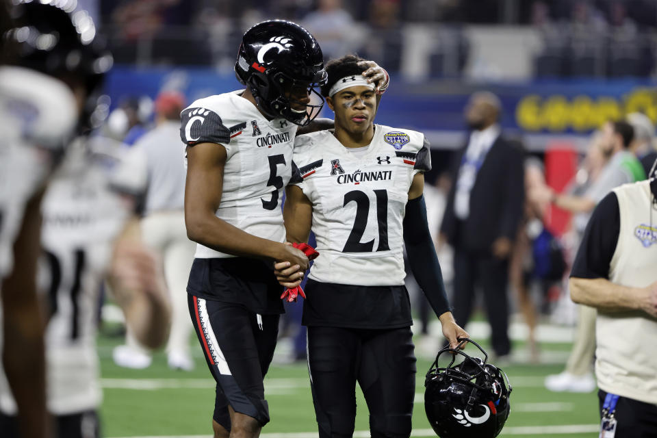 Cincinnati's Tyler Scott (21) and Jordan Jones (5) walks off the field after the Cotton Bowl NCAA College Football Playoff semifinal game against Alabama, Friday, Dec. 31, 2021, in Arlington, Texas. Alabama won 27-6. (AP Photo/Michael Ainsworth)