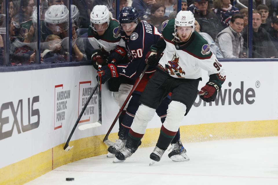Columbus Blue Jackets' Eric Robinson, center, tries to skate between Arizona Coyotes' Juuso Valimaki, left, and J.J. Moser during the second period of an NHL hockey game Tuesday, Oct. 25, 2022, in Columbus, Ohio. (AP Photo/Jay LaPrete)