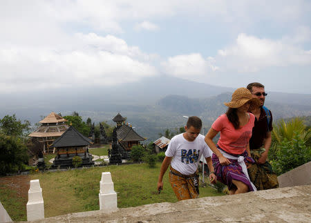 Tourists walk up the stairs at Penataran Agung Lempuyang Temple with Mount Agung, a volcano on the highest alert level, in the background in Karangasem Regency on the resort island of Bali, Indonesia September 25, 2017. REUTERS/Darren Whiteside