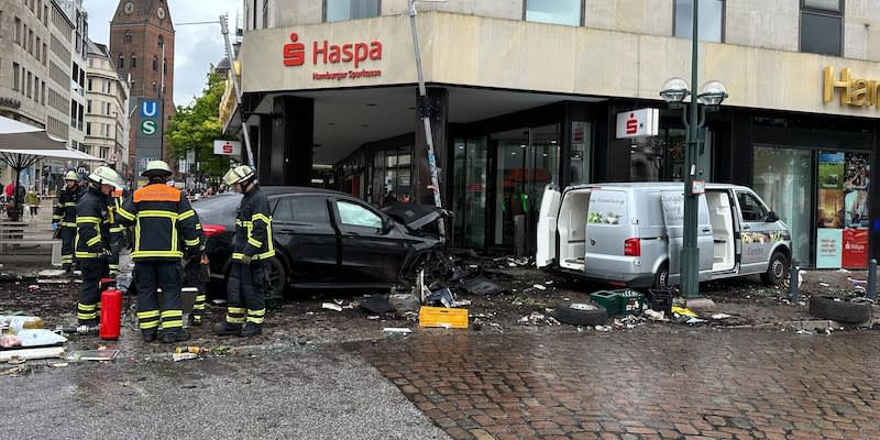 Helfer stehen an einem demolierten Auto vor einer Sparkasse. Ein Auto ist in Hamburg in eine Sparkasse gefahren, es gab mehrere Verletzte.<span class="copyright">dpa</span>