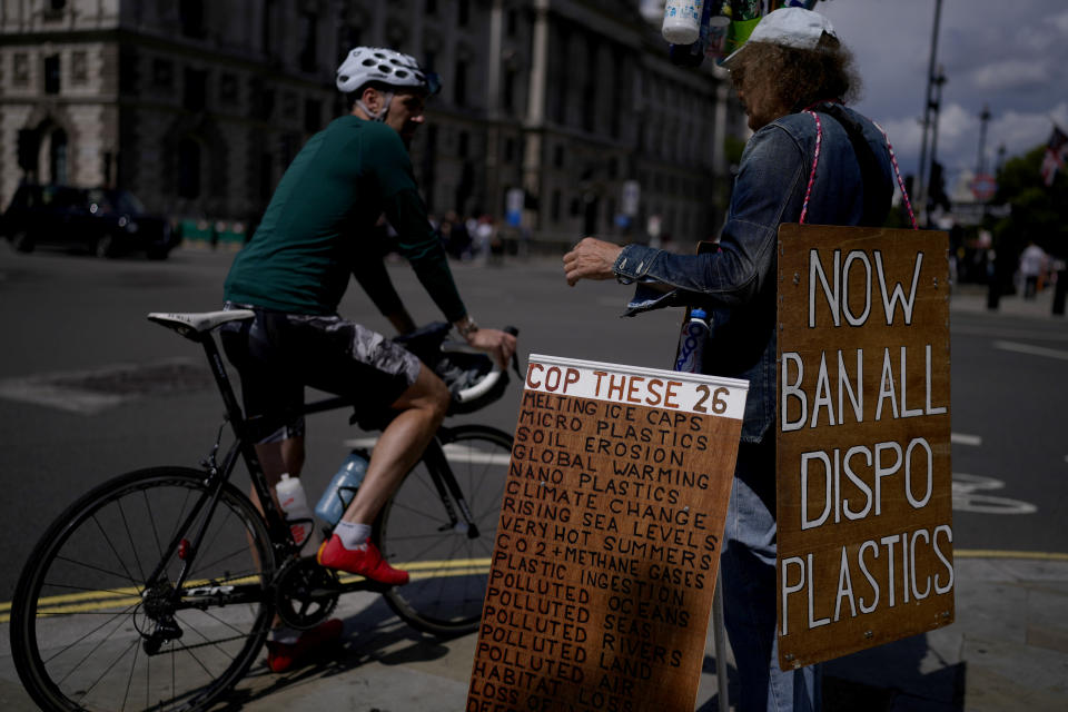 An environmental protester chats to a cyclist as he stands with placards and plastic bottles near the Houses of Parliament in London, Monday, Aug. 9, 2021. Earth's climate is getting so hot that temperatures in about a decade will probably blow past a level of warming that world leaders have sought to prevent, according to a report released Monday that the United Nations called a "code red for humanity." The authoritative Intergovernmental Panel on Climate Change (IPCC) report, which calls climate change clearly human-caused and "unequivocal," makes more precise and warmer forecasts for the 21st century than it did last time it was issued in 2013. (AP Photo/Matt Dunham)