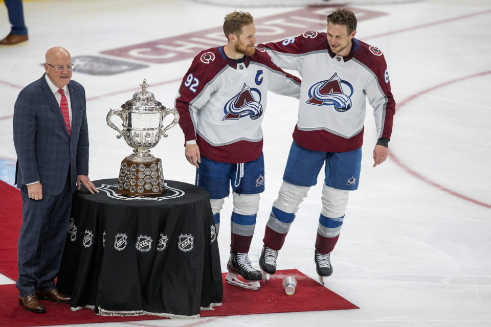 Colorado Avalanche's Gabriel Landeskog (92) and Erik Johnson (6) stand with the Campbell Conference Bowl as Deputy Commissioner Bill Daley looks on after overtime NHL hockey conference finals action in Edmonton, Alberta, on Monday, June 6, 2022. The Avalanche won the game 6-5, to take the series. (Amber Bracken/The Canadian Press via AP)