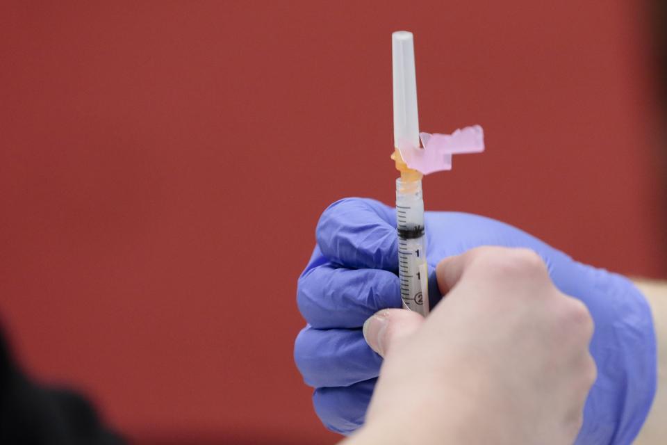 Pharmacist Stephen Polley hands a dose of the Moderna COVID-19 vaccine to a nursing student for distribution on Friday, Feb. 12, 2021 at the Schottenstein Center in Columbus, Ohio.