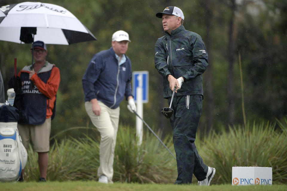 FILE - In this Dec. 15, 2018, file photo, Dru Love, center, watches as his father, Davis Love III, right, tees off on the second hole during the first round of the Father Son Challenge golf tournament, in Orlando, Fla. The Loves are playing in Singapore this week, the 14th time they played in the same event. (AP Photo/Phelan M. Ebenhack, File)