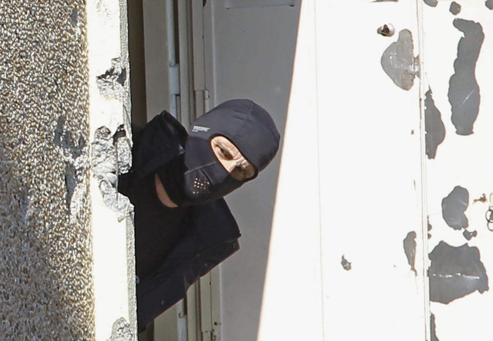 FILE - In this March 23, 2014 file photo, a masked police officer searches for clues at terrorist Mohamed Merah's apartment building in Toulouse, southern France. To stop the stream of French youths pursuing jihad in Syria, France is preparing to do something it has never done before: Tackle terrorism at its roots before it starts, by involving schools, parents and local Muslim leaders, The Associated Press has learned. Memories are still fresh of the radical Islamic Frenchman Merah who gunned down children at a Toulouse Jewish school in 2012, after training in Afghanistan and Pakistan. (AP Photo/Remy de la Mauviniere)