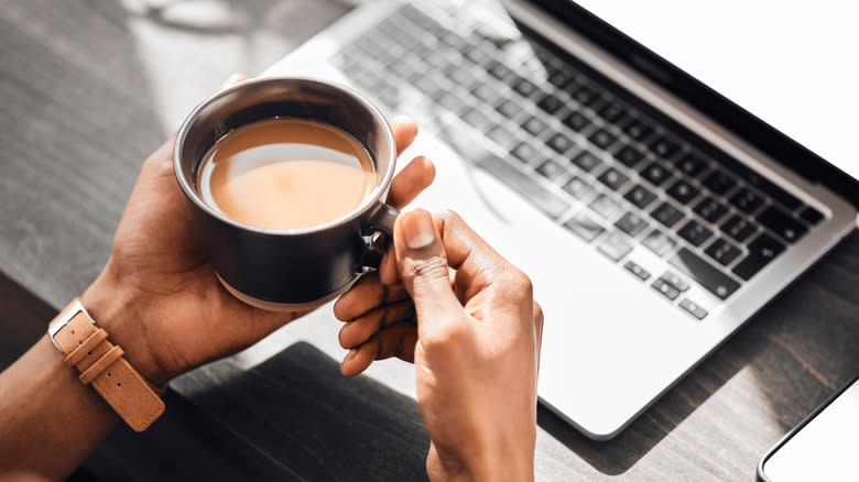 Laptop, keyboard, hands of person with coffee 