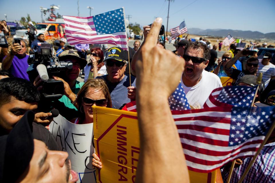 Demonstrators picketing against the arrival of undocumented migrants who were scheduled to be processed at the Murrieta Border Patrol Station block the buses carrying the migrants in Murrieta, California July 1, 2014. Some 140 undocumented immigrants, many of them women with children, will be flown from Texas to California and processed through a San Diego-area U.S. Border Patrol station as federal officials deal with a crush of Central American migrants at the border, a local mayor said on Monday. (REUTERS/Sam Hodgson)