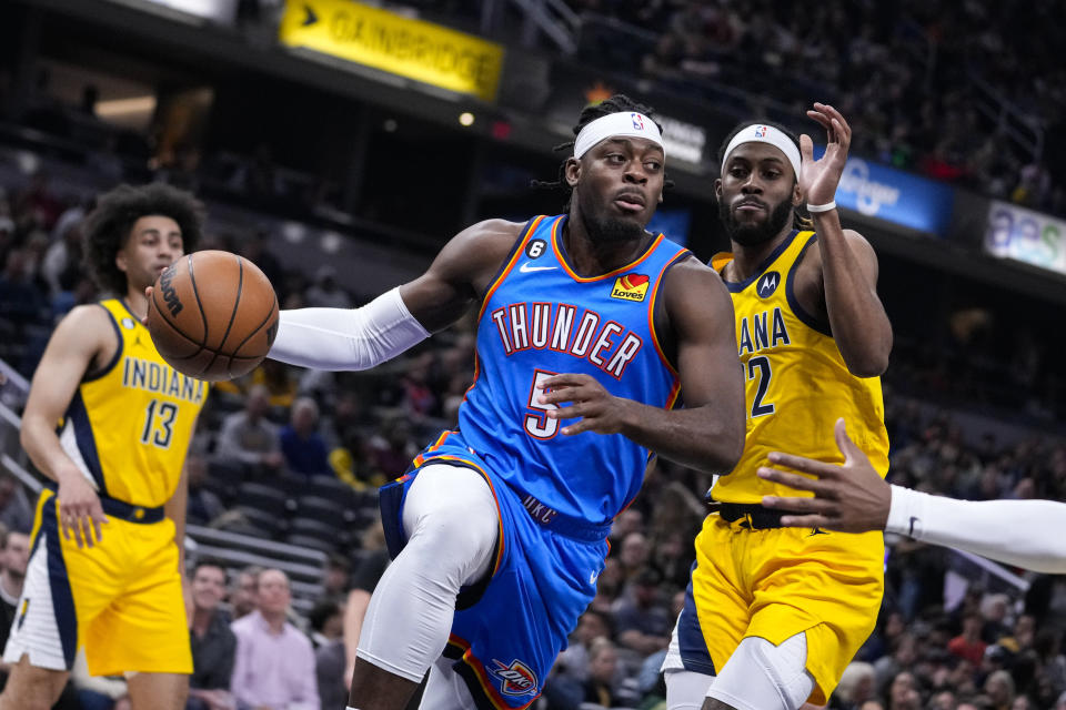 Oklahoma City Thunder guard Luguentz Dort (5) makes a pass in front of Indiana Pacers forward Isaiah Jackson (22) during the first half of an NBA basketball game in Indianapolis, Friday, March 31, 2023. (AP Photo/Michael Conroy)