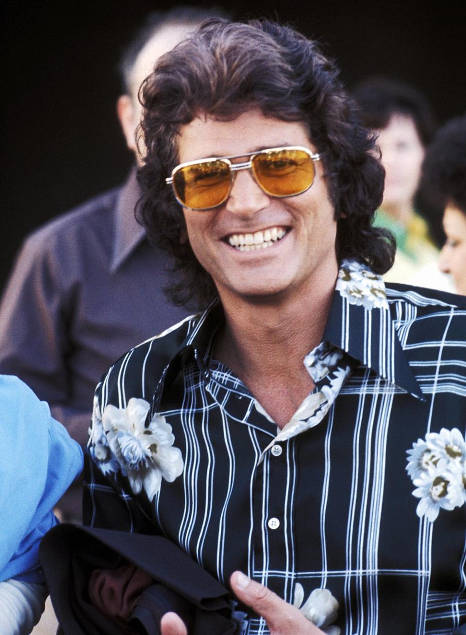 A close-up of Michael Landon smiling in a printed shirt and yellow sunglasses