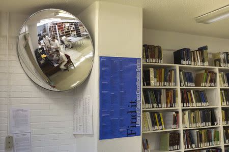 Offenders are reflected in a mirror while studying at a library inside the Southwestern Baptist Theological Seminary located in the Darrington Unit of the Texas Department of Criminal Justice men's prison in Rosharon, Texas August 12, 2014. REUTERS/Adrees Latif