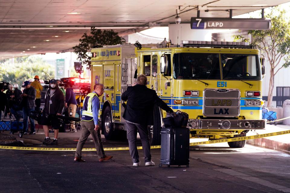 Los Angeles World Airports Chief of Airport Operations Richard Chong, left, assists a traveler, right, as fire crews remain on the scene at Terminal 7 to ensure there is no hazardous material inside the Los Angeles International Airport on Monday, Oct. 31, 2022.