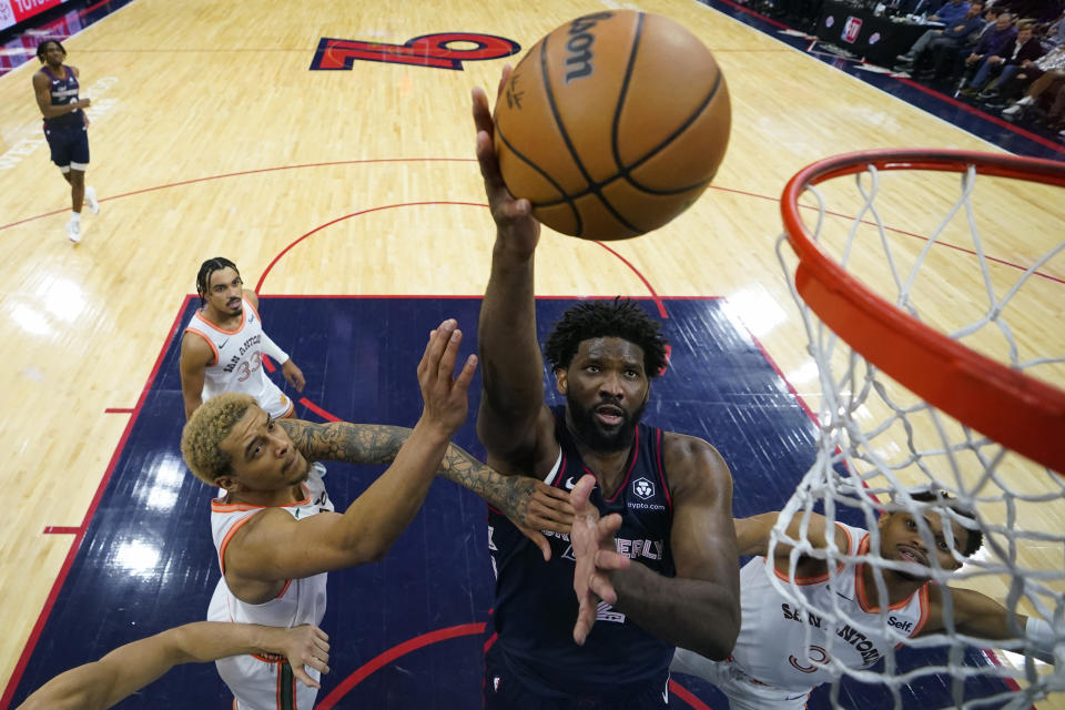 Joel Embiid, centro, de los 76ers de Filadelfia, toma un disparo entre Jeremy Sochan, izquierda, y Keldon Johnson, de los Spurs de San Antonio, durante la segunda mitad del juego de baloncesto de la NBA, el lunes 22 de enero de 2024, en Filadelfia. (AP Foto/Matt Slocum)