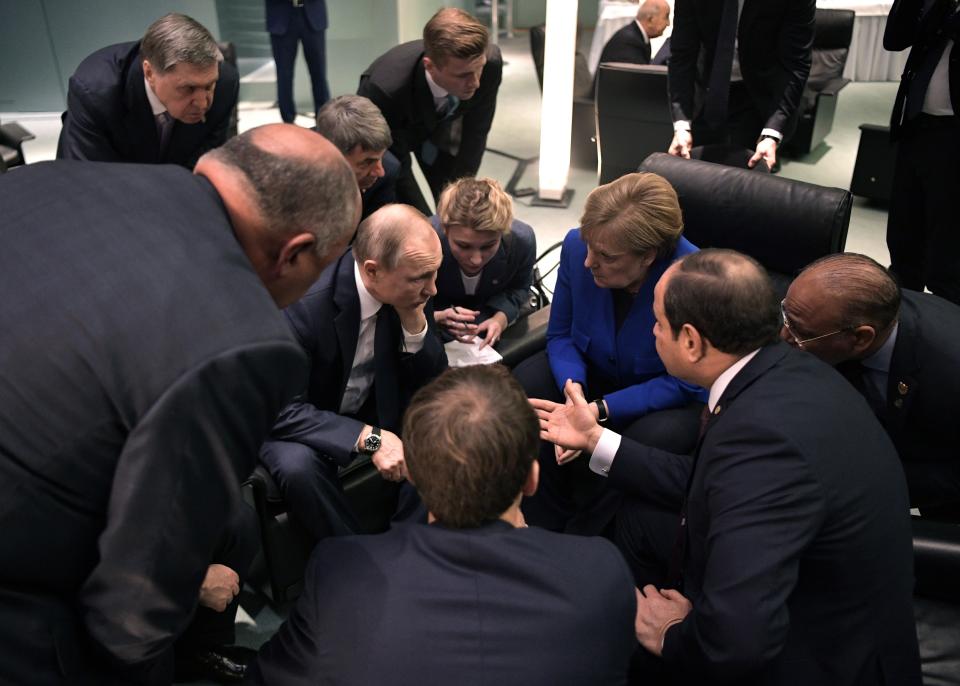 Russian President Vladimir Putin, center left, and German Chancellor Angela Merkel, center right, surrounded by other officials talk to each other during their meeting on the sideline of a conference on Libya at the chancellery in Berlin, Germany, Sunday, Jan. 19, 2020. German Chancellor Angela Merkel hosts the one-day conference of world powers on Sunday seeking to curb foreign military interference, solidify a cease-fire and help relaunch a political process to stop the chaos in the North African nation. (Alexei Nikolsky, Sputnik, Kremlin Pool Photo via AP)