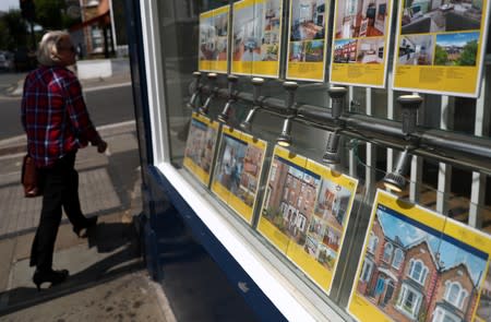 A woman passes the window of an estate agent in London